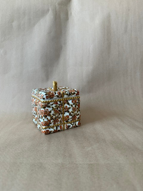 Square porcelain box painted as a wrapped gift with gold rope and bow
