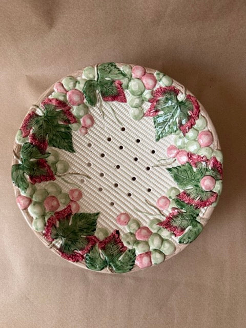 Footed ceramic berry bowl with molded grape and leaf border and pierced center