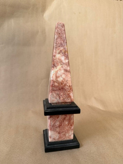 Pink marble obelisk on black base