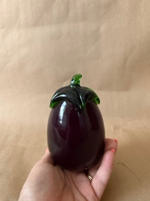 Glass eggplant shown in hand for scale