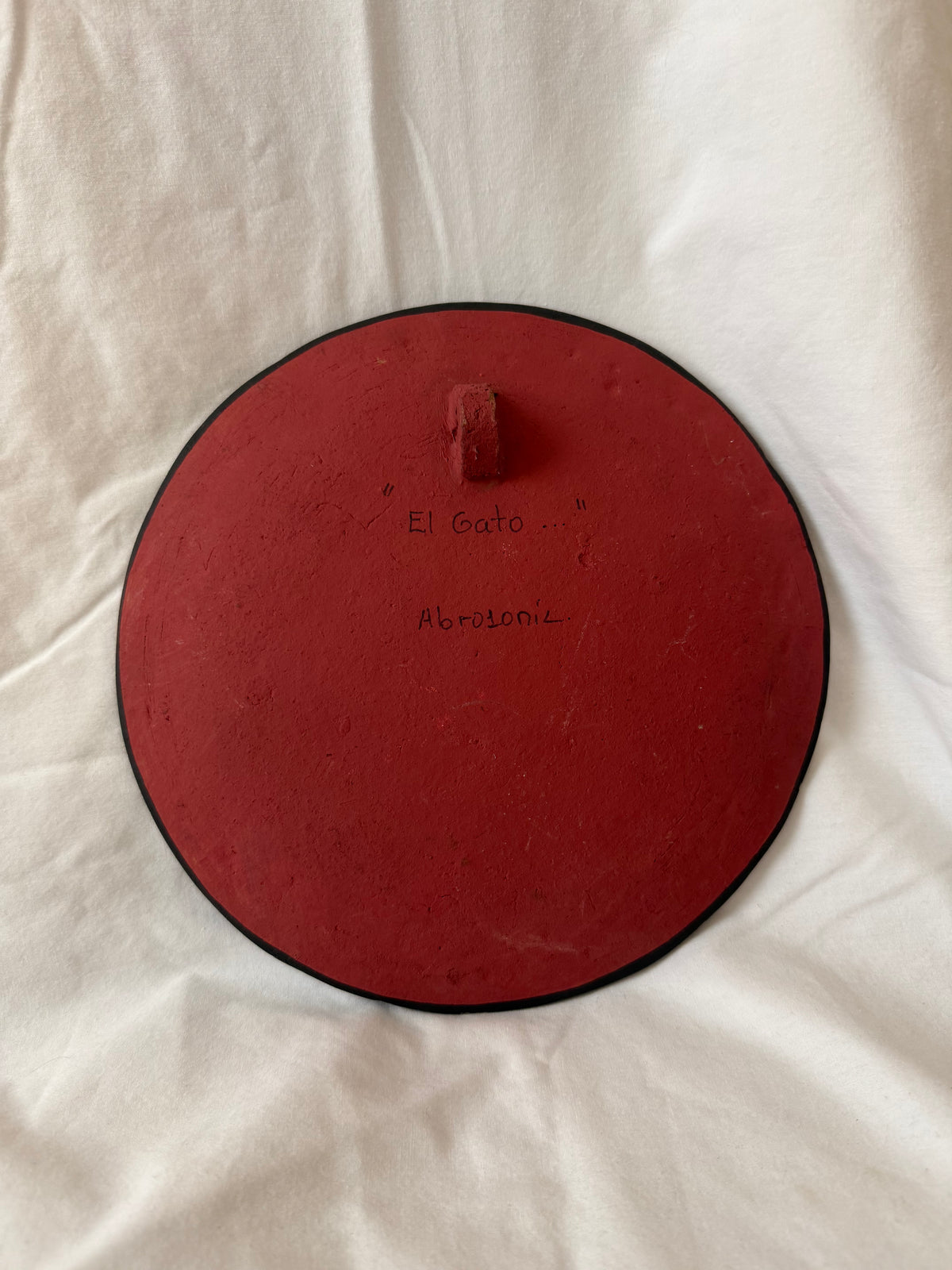Back of plate titled El Gato with hanging tab
