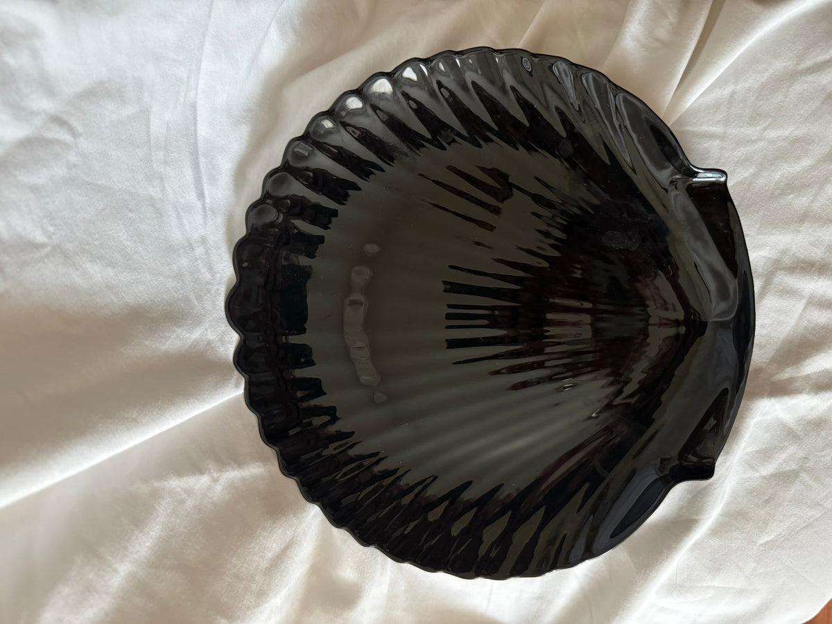 Black glass dish shaped like a scallop shell