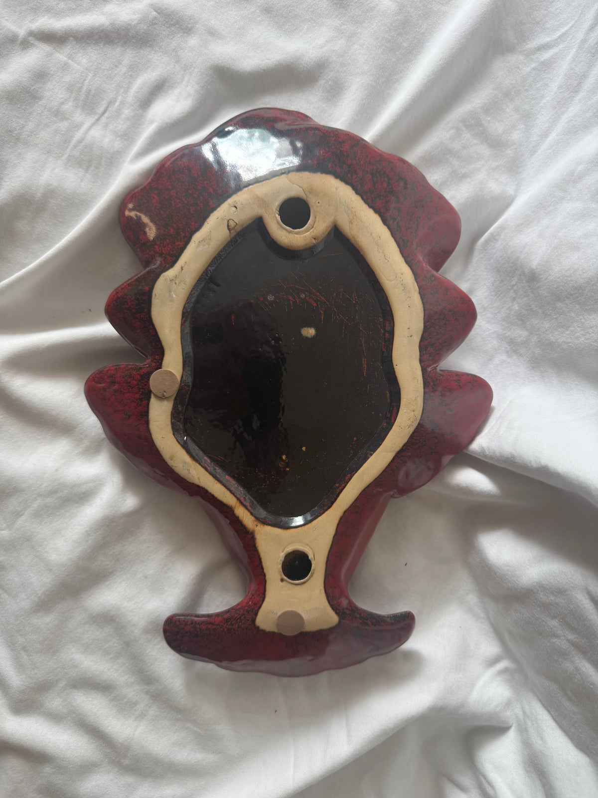 Back of red ceramic fish wall pocket showing hanging holes